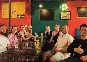 a group of people sitting around a table in a bar at Bed Station Hostel & Pool Bar Hội An " Former Sunflower" in Hoi An +20 photos