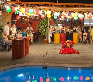 a group of people standing around a pool in a restaurant at Bed Station Hostel & Pool Bar Hội An " Former Sunflower" in Hoi An