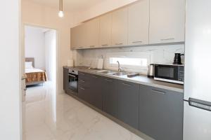 a kitchen with white cabinets and a sink and a microwave at Victoria Residence in Thessaloniki