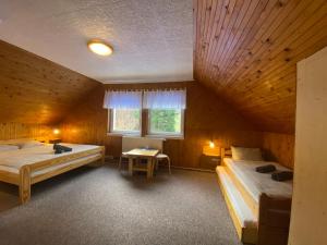 イェセニークにあるJe-sen, ubytování na horách s bazénem a infrasaunouのベッド2台、窓、テーブルが備わる客室です。