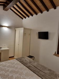 een slaapkamer met een bed en een tv aan de muur bij Macchie San Vincenzo - Villa Privata con Piscina e Giardino ad uso esclusivo o camere in Chiusi