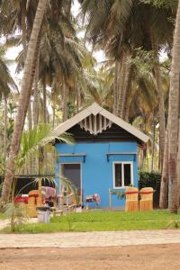 a blue house with palm trees in front of it at Ramu Green Lake Cottage in Mysore