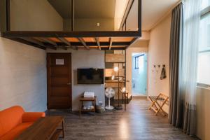 a living room with an orange couch and a tv at Waiting Homestay in Taitung City