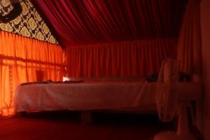 a bedroom with a bed with red curtains at Ramu Green Lake Cottage in Mysore