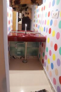 a bathroom with a red sink with a polka dot wall at Ramu Green Lake Cottage in Mysore