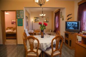 a dining room with a table with flowers and a television at VILLA ANTONIS in Kos