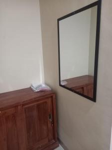 a mirror on a wall next to a wooden cabinet at Barada Poris 