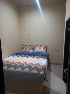 a bed with an orange and blue comforter in a room at Barada Poris 