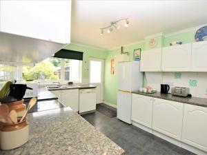 una cocina con armarios blancos y paredes verdes en 3 Bed in Great Snoring KT075, en Great Snoring