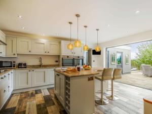 a kitchen with white cabinets and a island with a counter top at 3 Bed in Bovey Tracey 64380 in Bovey Tracey