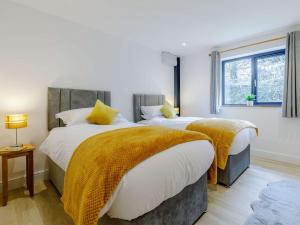 sypialnia z 2 łóżkami z żółtymi kocami i oknem w obiekcie 4 Bed in Berrynarbor 65786 w mieście Berrynarbor