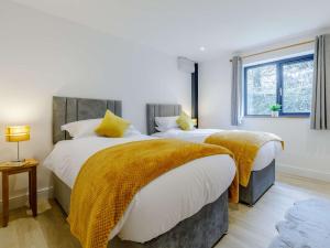 a bedroom with two beds with yellow blankets and a window at 4 Bed in Berrynarbor 65786 in Berrynarbor