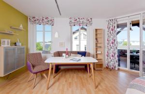 ein Wohnzimmer mit einem Tisch, Stühlen und Fenstern in der Unterkunft Ahlbecker Höhe App Möwennest in Ahlbeck