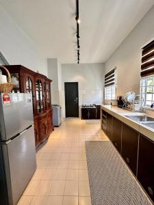 a large kitchen with a refrigerator and a sink at The P Lakehouse in Tanjong Sepat