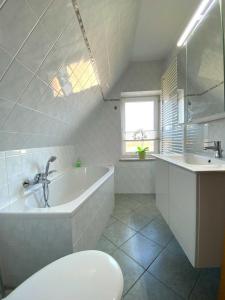 a white bathroom with a tub and a sink at Süderhaus Hiddensee App 13 in Neuendorf