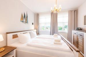 um quarto com uma grande cama branca e um lustre em Villa Albus App 8 em Ahlbeck