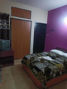 a bedroom with a bed and a tv and a purple wall at Holiday home in Ooty