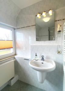 a white bathroom with a sink and a mirror at Süderhaus Hiddensee App 6 in Neuendorf