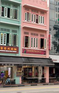un bâtiment rose avec quelques tables devant lui dans l'établissement Backpacker Cozy Corner Guesthouse, à Singapour