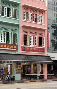 um edifício cor-de-rosa com algumas mesas à frente. em Backpacker Cozy Corner Guesthouse em Singapura