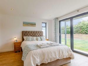 ein Schlafzimmer mit einem großen Bett und einem großen Fenster in der Unterkunft 3 Bed in Westward Ho 75539 in Northam