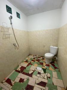 een badkamer met een toilet en een mozaïekvloer bij Bintang Guesthouse in Gili Trawangan