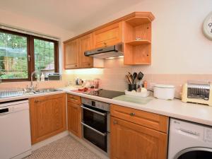 - une cuisine avec des placards en bois et des appareils blancs dans l'établissement 2 Bed in Moreton-In-Marsh 75870, à Whichford