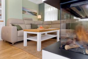 uma sala de estar com um sofá e uma mesa em Villa Waldschloss App 2 em Bansin