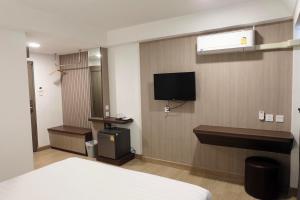 Habitación de hotel con cama y TV en la pared en U-Thong Hotel, en Phitsanulok