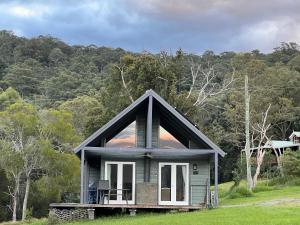 a small house in the middle of a field at Bluegums Cabins Barrington Tops in Bandon Grove