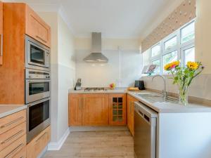 uma cozinha com armários de madeira e um vaso de flores em 2 Bed in Bournemouth 78541 em Ferndown