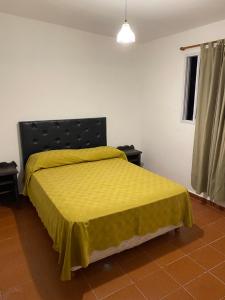 une chambre avec un lit avec un couvre-lit jaune dans l'établissement departamentoAA, à Villa Carlos Paz