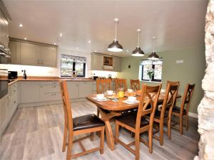 4 Bed in Conwy 66510 في لنروست: مطبخ وغرفة طعام مع طاولة وكراسي خشبية