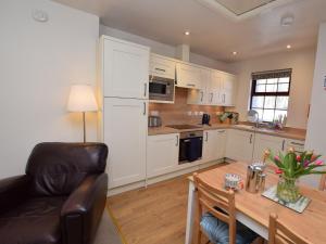 a kitchen with white cabinets and a table and a chair at 1 Bed in Applecross CA186 in Applecross