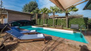 - une piscine avec 2 chaises longues à côté d'une maison dans l'établissement VILLA VIVI' 8, Emma Villas, à Monte San Savino
