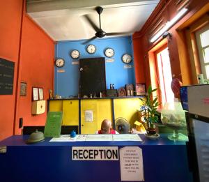 a man sitting at a reception desk in a room with clocks at Backpacker Cozy Corner Guesthouse in Singapore