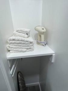 - une étagère blanche avec des serviettes dans la salle de bains dans l'établissement Modern/new 1br Apt- Shops 5mn, à Massapequa
