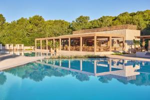 a swimming pool in front of a building with a house at Ikos Porto Petro in Portopetro +37 photos