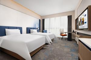 a hotel room with two beds and a desk at Hampton by Hilton Guangzhou Renhe Baiyun Airport-Free airport shuttle bus in Guangzhou