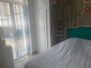 a bedroom with a bed with a blue comforter and windows at 3 pieces avec terrasse entre plage et centre ville in Arcachon