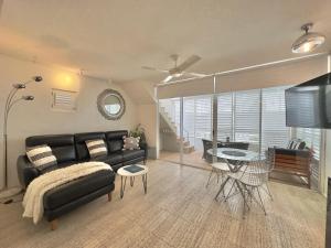 uma sala de estar com um sofá preto e uma mesa em Oasis Rooftop Spa Apartment em Noosa Heads