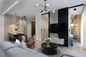 a living room with a couch and a tv at Elite Apartments Sienna Grobla Prestige in Gdańsk