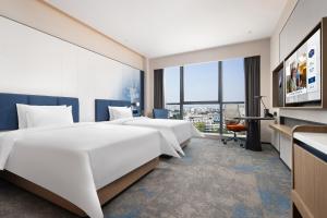 a hotel room with two beds and a tv at Hampton by Hilton Guangzhou Renhe Baiyun Airport-Free airport shuttle bus in Guangzhou