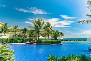 una piscina en el complejo con palmeras y el océano en Mysterio Pool Villas - Wyndham Garden Resort en Cam Ranh