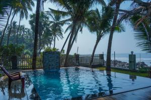 a swimming pool with palm trees and the ocean at En Ocean Infinity Pool Villa Overlooking Sea ,Beach Touch in Alibaug