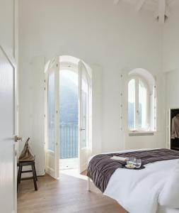 a white bedroom with a bed and an open window at Villa Làrio Lake Como in Pognana Lario
