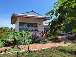 a house with a porch with a palm tree on it at Coconut Garden Resort 椰苑星辰 in Semporna