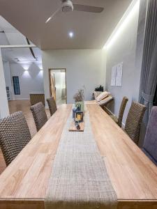 una gran mesa de madera en una habitación con sillas en Compass North - PoolVilla & BBQ en Ban Pa Lan