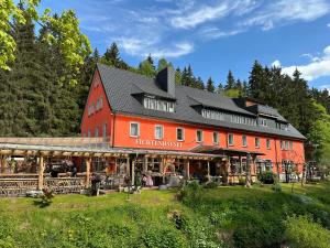 eine große rote Scheune mit Leuten davor in der Unterkunft Erlebnishotel & Restaurant Fichtenhäusel am Pöhlagrund in Kühberg