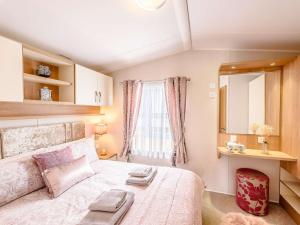 2 Bed in Newborough 82559 في Brynsiencyn: غرفة نوم بسرير ومرآة ونافذة